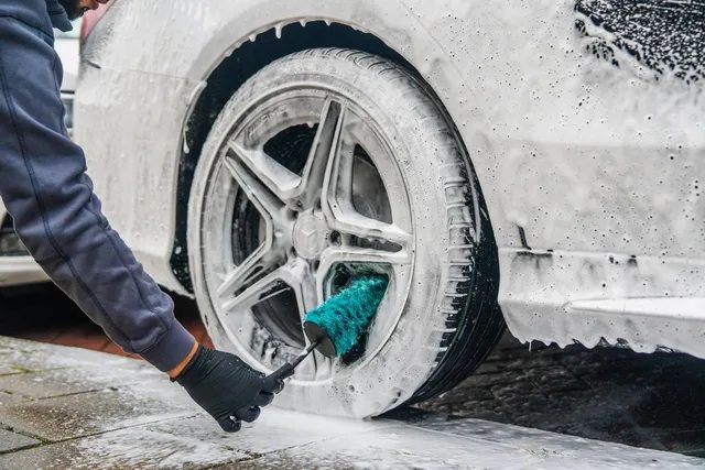 Velgenborstel tussen de spaken van een ingezeepte auto